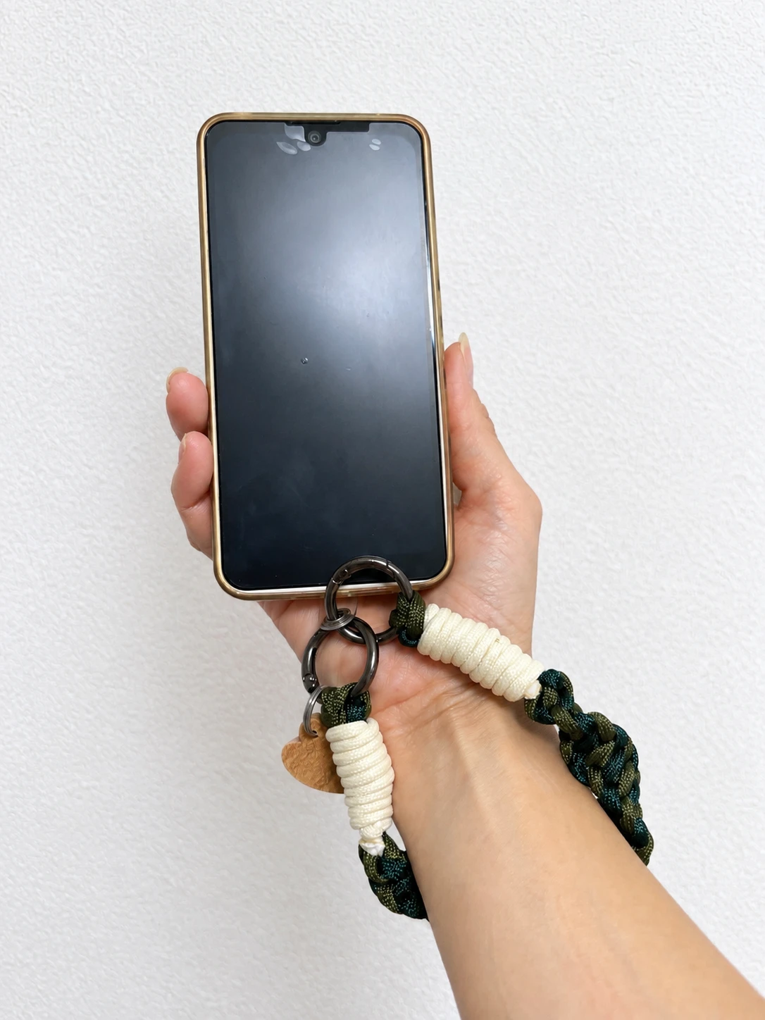 グリーンのハンドストラップをつけたスマホを手に持ったところ