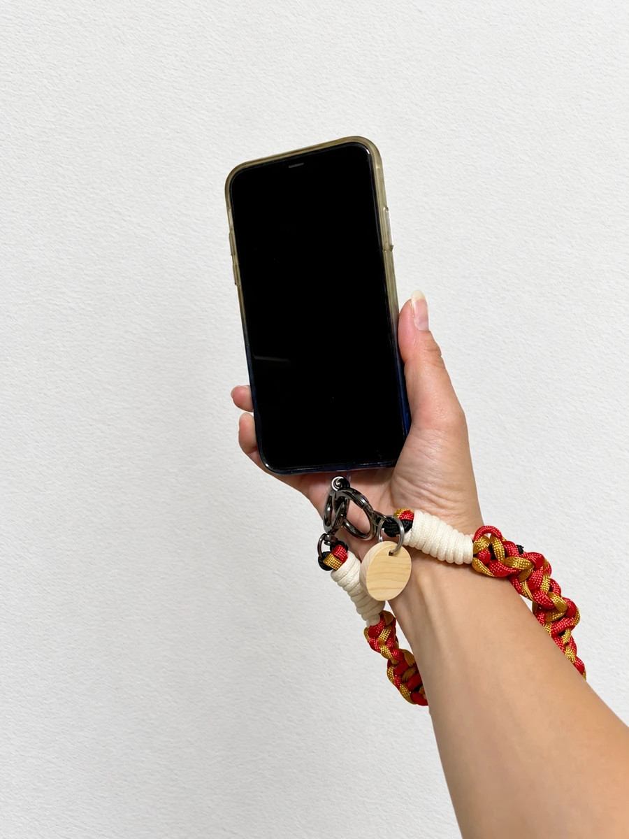 レッドのハンドストラップをつけたスマホを手に持ったところ