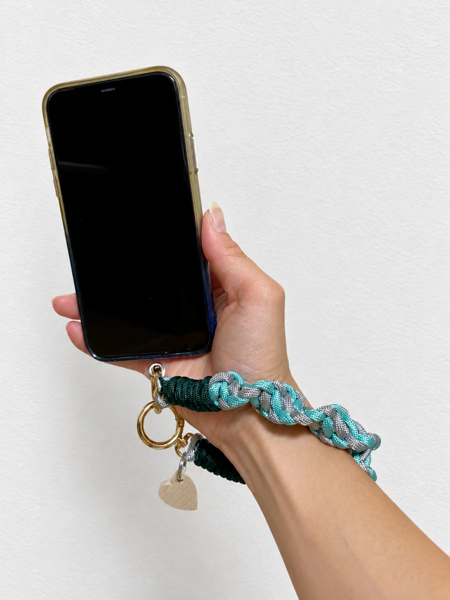 ターコイズのハンドストラップをつけたスマホを手に持ったところ